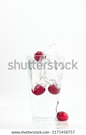 cherries falling into water, splashes, fall into water transparent glass, white background