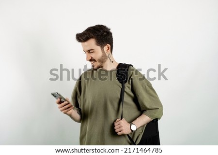 Cheerful caucasian man wearing casual clothes posing isolated over white background reading message on smart phone.