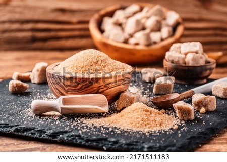 Bowl and scoop with sand and lump brown sugar on wooden background. brown sugar cube. Make unhealthy nutrition, obesity, diabetes, dental care and much more.