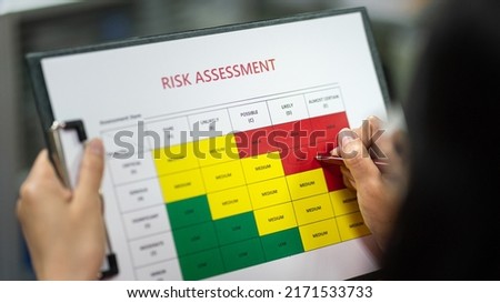 Action of a person is using ballpoint pen to marking on the risk assessment matrix table at "High risk" level. Industrial or business working action scene photo. Close-up and selective focus. Royalty-Free Stock Photo #2171533733