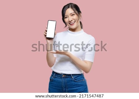 Attractive Young Asian woman showing mobile smartphone blank screen on isolated pink background.