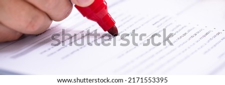 Close-up Of A Businessperson's Hand Holding Marker On Document