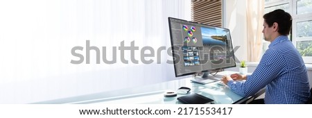 Young male editor editing video on computer at workplace