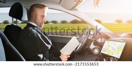 Young Businessman Sitting Inside Self Driving Car And Reading Book Royalty-Free Stock Photo #2171553653