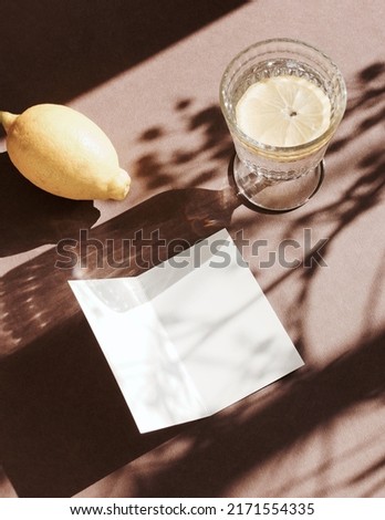 Blank paper sheet cards mockup,lemon,lemonade glass and floral shadow top view on brown   background. Copy space. Flat lay   minimal business brand template neutral color. Card mock up.