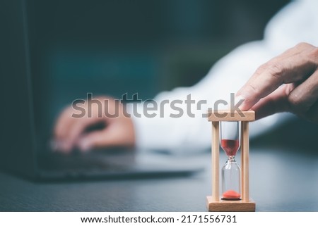 The young businessman's fingers touch the hourglass, The value of time in life.Management and distribution of time. Royalty-Free Stock Photo #2171556731