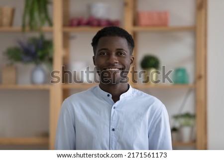 Head shot portrait successful young African businessman wear casual blue shirt smile looks at camera pose at workplace in cozy office. Professional occupation person, teacher profile picture concept