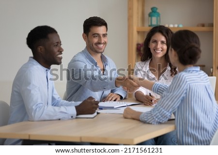 Diverse millennial ambitious business partners coming to agreement, handshake accomplish negotiations at group meeting, establishing partnership, make deal feeling satisfied. Succeed result concept Royalty-Free Stock Photo #2171561231