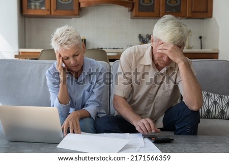Older stressed unhappy wife and husband manage family finances feeling desperate due debts, unpaid bills, lack of money to pay monthly bills or bank mortgage. Financial crisis, bankruptcy concept Royalty-Free Stock Photo #2171566359