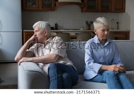 Serious thoughtful unhappy older 60s wife and husband sit on couch separately. Couple experiencing marriage crisis, lack of understanding and patience, break up and hard decision about divorce concept Royalty-Free Stock Photo #2171566371