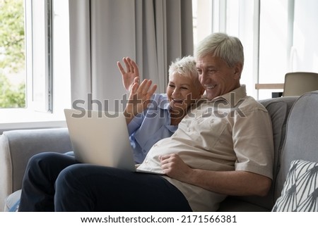 Mature couple sit on sofa at home talking to grownup children use videoconference app on laptop, enjoy distance warm conversation. Older gen easy comfort usage of modern tech, communication concept Royalty-Free Stock Photo #2171566381