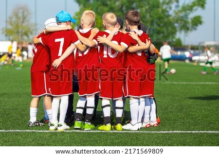 Sporty players huddling in a circle on the field. Motivated youth soccer team cheering on court. Team captain talking to a group of soccer friends. Happy football team in red soccer uniforms