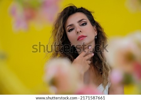 Close-up portrait of a beautiful girl on a yellow background. woman posing on a background of colorful flowers.