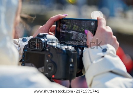 Woman videographer filming on DSLR camera and smartphone outdoor event, video blogging. Girl blogger shooting video content for social media networks, photographing and video making