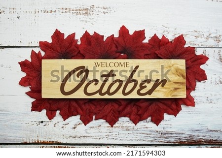 Hello October text on wooden planks decorated with maple leaves on wooden background