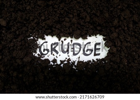 Bury grudge and stop holding concept. Grudge text word on soil backdrop. Royalty-Free Stock Photo #2171626709