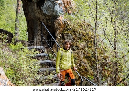 Rest in nature, descent from the cave on a metal staircase, a person walks up the steps, a tourist with a backpack on a hike, vacations in nature. High quality photo