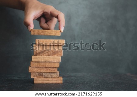 Hand place wooden block stacked concept of prevent collapse or crash of financial business and risk management or strategic planning and insurance. Royalty-Free Stock Photo #2171629155