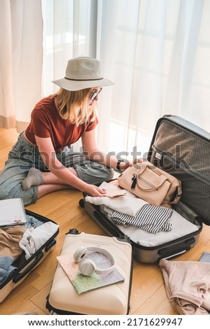 Travel. Staycation.local travel new normal.Girl packing luggage in suitcase and travel documents Travel,tourism,vacation,relocation.Mental health and travel vacation Film grain Royalty-Free Stock Photo #2171629947