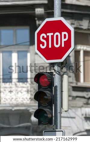 Red traffic light on and stop sign.