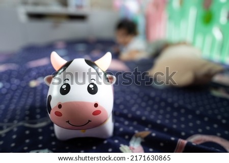 A music player device cow, toy for the infant baby. Photo with a baby playing as blurred background. Recreation object photo.