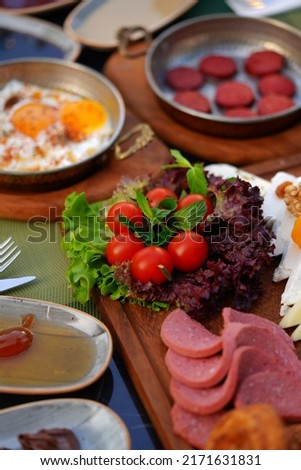 Organic, fresh Traditional Turkish Village Breakfast on wooden table with copper egg pan, ceramic casserole and bamboo breakfast set.