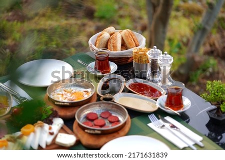 Organic, fresh Traditional Turkish Village Breakfast on wooden table with copper egg pan, ceramic casserole and bamboo breakfast set.