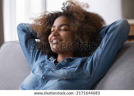 Close up beautiful peaceful African teenage girl relaxing alone at modern home breathing fresh conditioned air in cozy warm living room. Enjoy stress free weekend, repose, healthy daytime nap concept Royalty-Free Stock Photo #2171644683