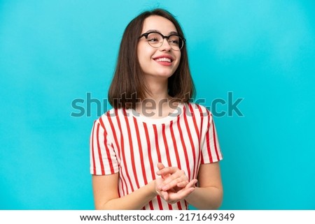 Young Ukrainian woman isolated on blue background applauding