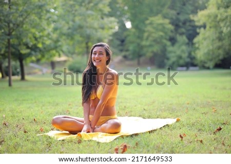 young woman in bikini on the grass in a park