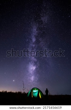 Man near tent, admiring the night sky