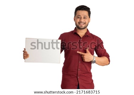 A happy young man holding and displaying a signboard or placard in his hands on a white background.