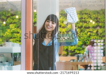 Smiling caucasian young woman barista cleaning shop glass and signage, ready to serve customers. Coffee shop and restaurant concept Start small business owner Lifestyle Leisure Food and drink Cafe