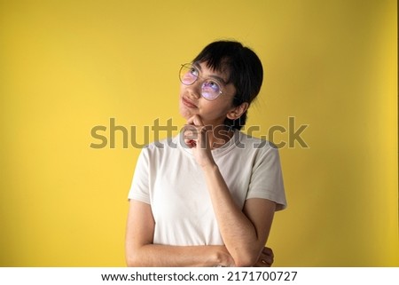 Thinking,Imagination,contemplation,Planning,creative Concept.,Closeup Photo of attractive Asian Woman Looking up,Thinking and touch chin isolated over yellow background with copyspace.