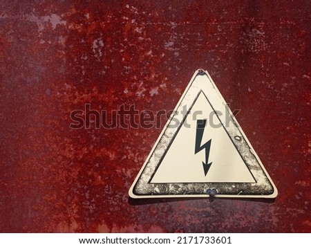 Symbol of electric voltage, danger warning on the background of a rusty door