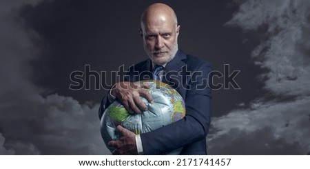 Greedy corporate businessman crushing a globe: earth exploitation and power concept Royalty-Free Stock Photo #2171741457