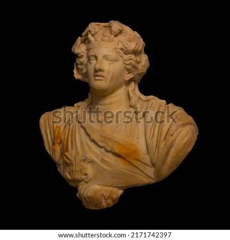 Marble bust of god Dionysus isolated on black background. Two small horns on his head and a wreath of ivy, his hair forms a knot at the neck. He is dressed in a garment and a panther's hide