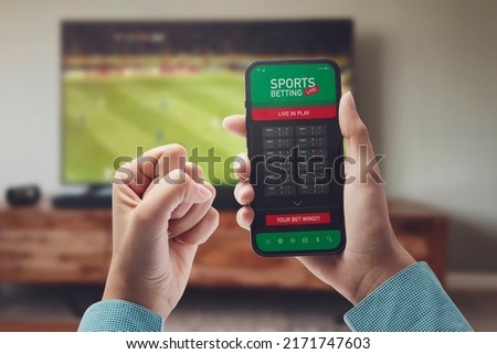 Live in-play betting app on smartphone display, a woman is betting at home and winning, POV shot Royalty-Free Stock Photo #2171747603
