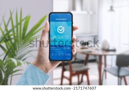 Woman checking air quality in her home using using a smartphone Royalty-Free Stock Photo #2171747607