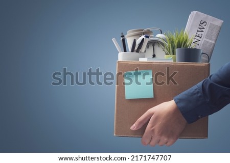 Office worker carrying personal belongings in a box after being fired, unemployment and career concept Royalty-Free Stock Photo #2171747707