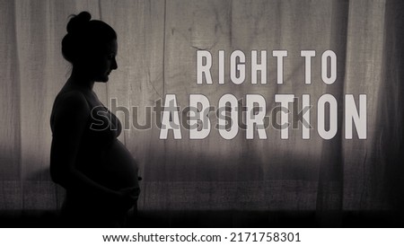 Text right to abortion and pregnant woman stands in the light of a night window, black and white silhouette