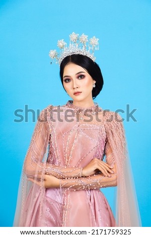 Portrait of asian woman in beautiful makeup wearing pink wedding dress, isolated on blue background.