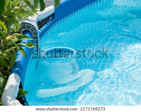View of the blue skimmer for cleaning the pool in clean water. Close-up of a skimmer mounted on a framed pool. Royalty-Free Stock Photo #2171768273