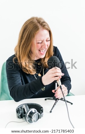 Woman screaming into microphone with headphones on desk