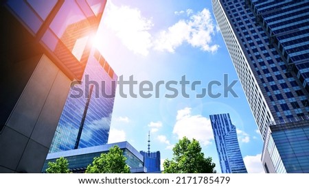 Modern office building with glass facade on a clear sky background. Transparent glass wall of office building. Bright sunny day with sunbeams on the blue sky.Velvia graphic filter