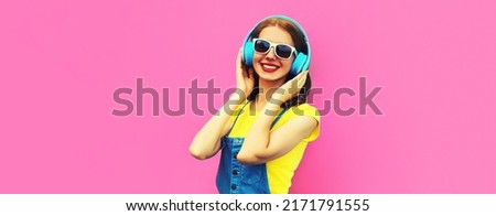 Happy smiling young woman with headphones listening to music on pink background, blank copy space for advertising text
