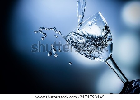 Spraying water from a glass. Isolated on a blue background. An upturned glass from which water splashes.