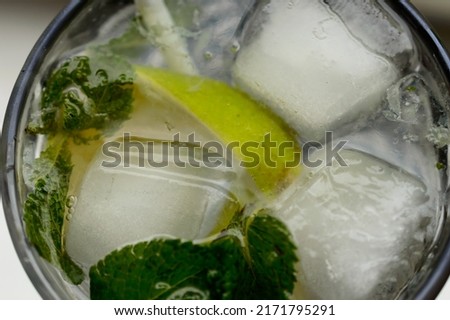 Close up photo of a fresh alcoholic mojito with an ice, lime and mint in the pretty goblet. Background picture.