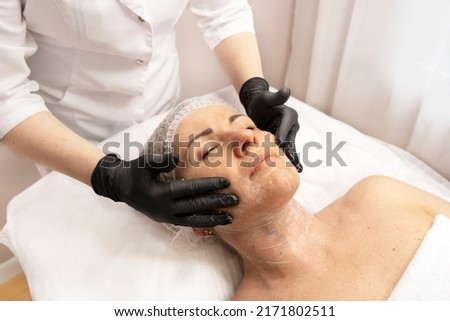 Young beautiful woman getting facial care and peeling by beautician at the spa salon. Skin and body care, spa beauty treatment. Royalty-Free Stock Photo #2171802511
