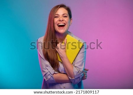 Happy emotional teacher or student woman with mouth open holding book, portrait with neon lights colors effect. Female model isolated on neon background